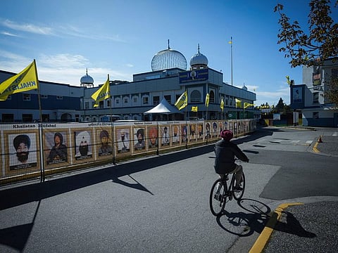 A man rides a bike outside the Guru Nanak Sikh Gurdwara Sahib in Surrey, British Columbia, on Monday, Sept. 18, 2023, where Hardeep Singh Nijjar was gunned down in his vehicle while leaving the temple parking lot in June