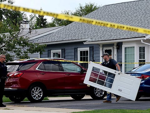 A Romeoville Police officer carries out a door from inside of the home where four people were shot to death, on Monday, Sept. 18, 2023, in Romeoville Ill.