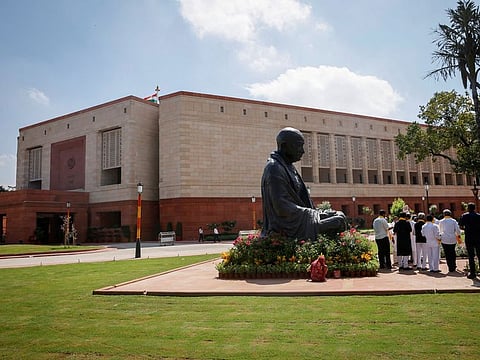A statue of Mahatma Gandhi is pictured next to India's new parliament building in New Delhi. The new building is expected to give better infrastructure, access to modern technology, and other updated facilities.