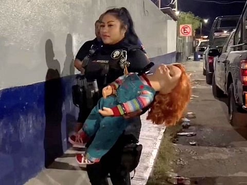 A police officer holds the handcuffed "demon doll" Chucky after arresting Carlos "N".