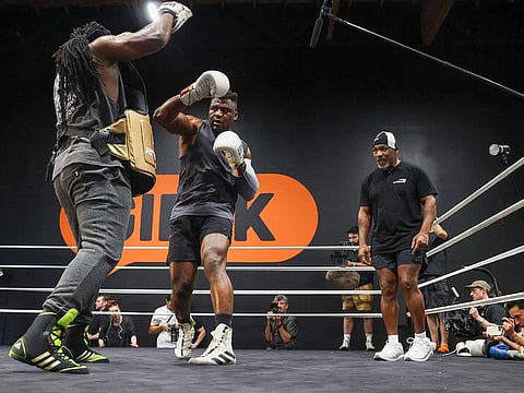Cameroonian-French mixed martial arts star and boxer Francis Ngannou (C) spars with Dewey Cooper while former US boxer Mike Tyson (R) watches during a training session at Ngannou’s gym in Las Vegas, Nevada.