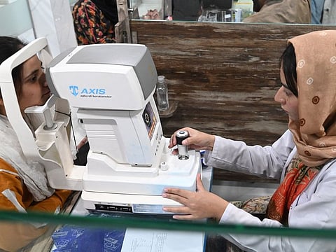 A doctor (right) examines a patient suffering from an eye infection at a hospital in Lahore on September 27, 2023.