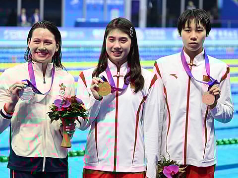 Gold medallist China's Zhang Yufei (centre) celebrates with silver medallist Hong Kong's Siobhan Haughey (left) and bronze medallist China's Cheng Yujie during the medals ceremony for the women's 50m freestyle swimming event during the Asian Games in Hangzhou on Thursday.