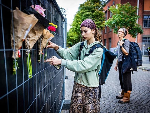 People attach flowers to a fence set outside the Erasmus university hospital in Rotterdam on September 29, 2023, a day after a woman, her 14-year-old daughter, and a teacher at the hospital were shot dead.