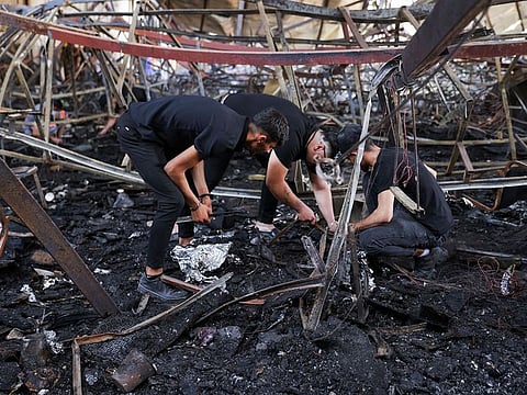Volunteers search for the remains of missing bodies following a fatal fire at a wedding celebration, in the district of Hamdaniya, in Nineveh province, Iraq