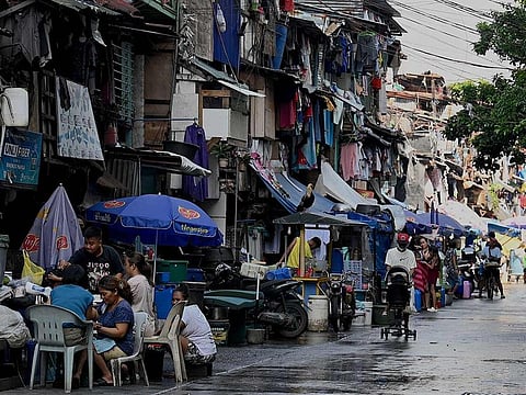 People walk past makeshift houses in Manila.