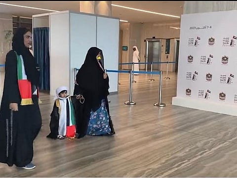 A female voter with a toddler is seen being escorted towards a polling station at the Abu Dhabi Energy Centre on Day 2 of the Federal National Council (FNC) elections on October 5, 2023.