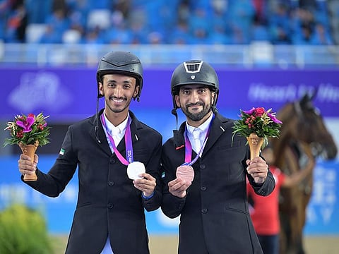 Omar Al Marzouqi and Abdullah Al Marri with silver and bronze medals in the Asian Games show jumping individual championships on Friday.