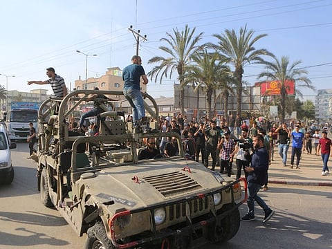 Palestinians ride on an Israeli military vehicle taken from an army base overrun by Hamas militants near the Gaza Strip fence on October 7, 2023.