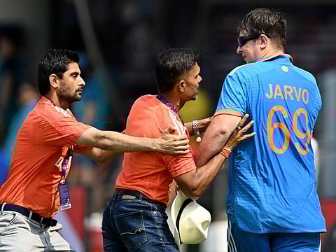 Officials stop a pitch invader World Cup match between India and Australia at the MA Chidambaram Stadium in Chennai on Sunday.