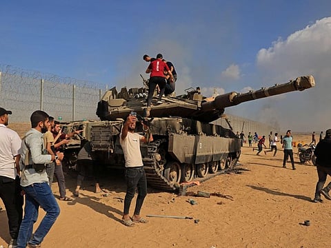 Palestinians take control of an Israeli tank after crossing the border fence with Israel from Khan Younis in the southern Gaza Strip on October 7, 2023.