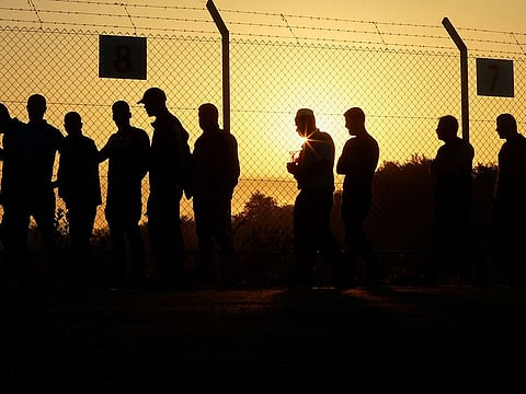 Palestinian workers walk near the fence during sunrise to enter the Erez crossing to Israel.