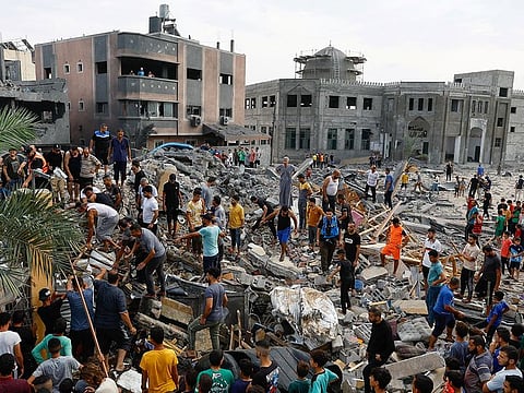 Palestinians walk among the rubble of a building destroyed in Israeli strikes, in the southern Gaza strip.