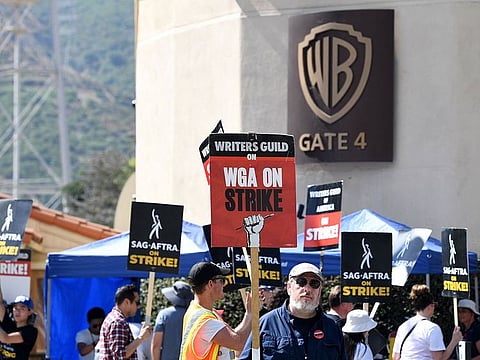 FILES: Members of the Writers Guild of America and the Screen Actors Guild walk a picket line outside of Warner Bros Studio in Burbank, California, on July 26, 2023. Hollywood writers overwhelmingly voted to approve a hard-fought new deal with studios, their union said October 9, 2023, officially ending one of the industry's longest ever strikes.