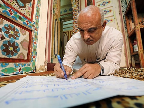 Saad Mohammad writes as he sits on the floor of his studio.