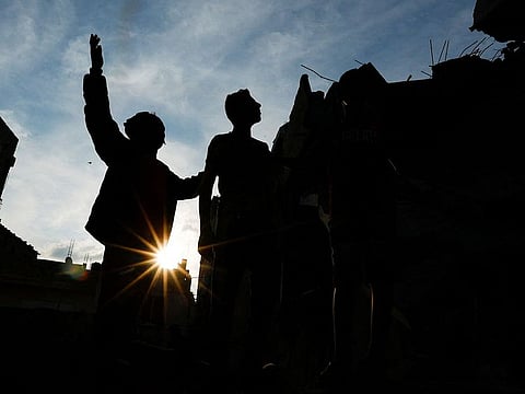 Palestinians stand on the rubble of a damaged house hit by Israeli strikes, in Khan Younis
