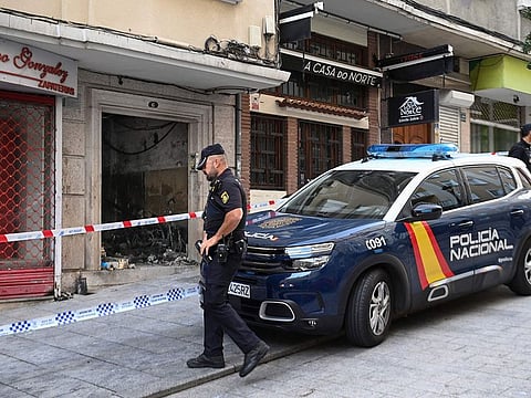 A police officer walks next to a building where four minors were killed in a fire in Vigo.