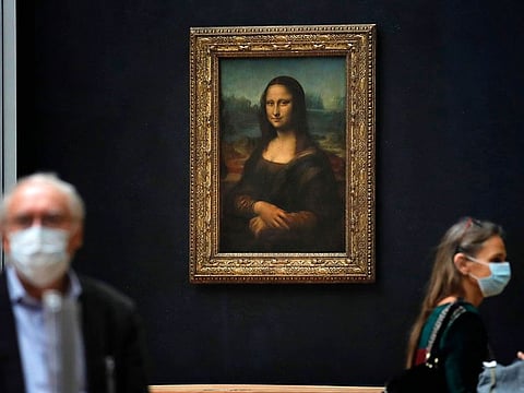 Journalists walk past Leonardo da Vinci's Mona Lisa during a visit of the Louvre museum.