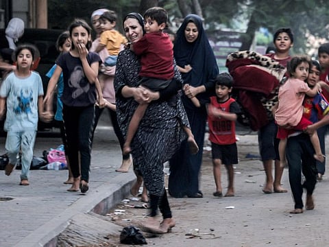 Palestinian women with their children fleeing from their homes following Israeli air strikes on Gaza City on October 11, 2023.