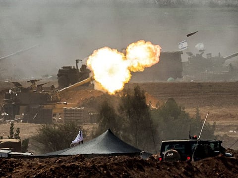 An Israeli army M109 155mm self-propelled howitzer fires rounds near the border with Gaza in southern Israel on October 12, 2023.