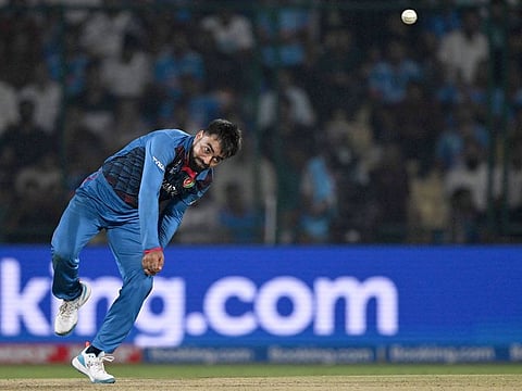 Afghanistan’s Rashid Khan bowls during the 2023 ICC Men's Cricket World Cup one-day international match against India at the Arun Jaitley Stadium in New Delhi on October 11, 2023. The leg-spinner’s late introduction into the attack raised eyebrows.