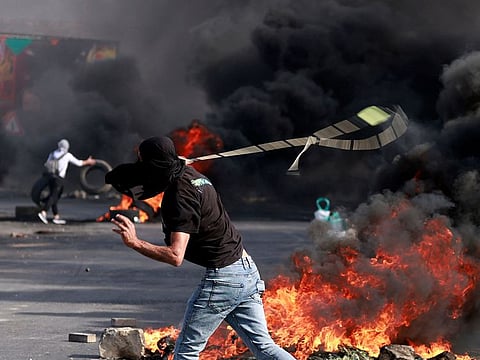 A Palestinian uses a slingshot during clashes with Israeli soldiers at the north entarnce of the city of Ramallah, in West Bank on October 13, 2023.