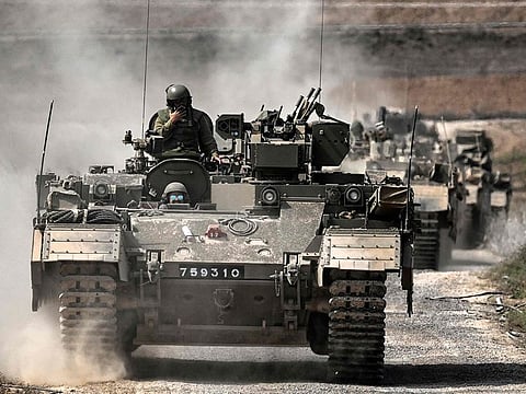 A column of Israeli army military armoured vehicles moves near the Gaza border in southern Israel on October 14, 2023.