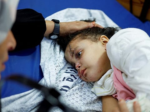 Palestinian girl Fulla Al Laham, 4, who was wounded in an Israeli strike that killed 14 family members, including her parents and all her siblings, lies on a bed as her grandmother sits next to her, at a hospital in Khan Younis in the southern Gaza Strip.
