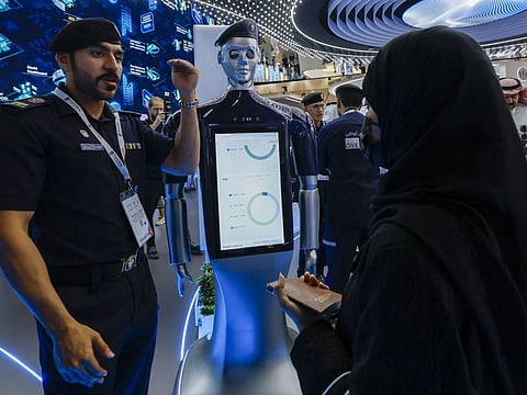 An official (left) provides information about the robot (centre) displayed at the Abu Dhabi Airport stand during Gitex Global 2023 at Dubai World Trade Centre