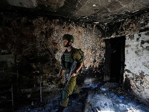 An Israeli soldier inspects a house damaged by Hamas militants in Kibbutz Kfar Azza, Israel, Wednesday, October 18, 2023.