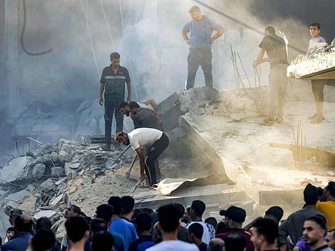 People dig and search through the rubble of a destroyed building following Israeli bombardment in Rafah in the southern of Gaza Strip on October 19, 2023.