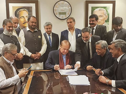 This handout picture taken and released on October 21, 2023, by the Pakistan Muslim League-Nawaz (PMLN) party shows Pakistan's former Prime Minister Nawaz Sharif (C) signing a legal document after his arrival at the Islamabad airport.