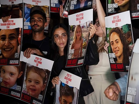 Relatives of people taken hostage by Hamas militants hold the pictures of their loved ones during a protest in Tel Aviv.
