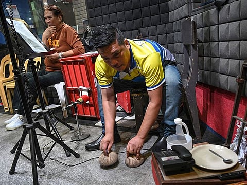 Gerry Mutia uses coconut shells for sound effects during the recording of a radio drama at a studio of a radio station in Manila.