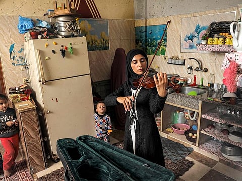 Jawaher Al Aqraa plays a violin as she stands in the kitchen of her home in Deir Al Balah in the central Gaza Strip on October 24, 2023.