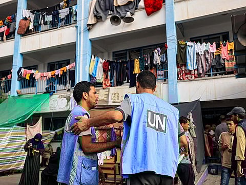 Workers of the United Nations Relief and Works Agency for Palestine Refugees (UNRWA) agency talk together in the playground of an UNRWA-run school that has been converted into a shelter for displaced Palestinians in Khan Yunis in the southern Gaza Strip on October 25, 2023, amid the ongoing battles between Israel and the Palestinian group Hamas.