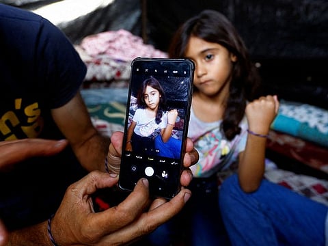 Daughter of Palestinian man Ali Daba shows her bracelet at their shelter in Khan Younis in the southern Gaza Strip October 24, 2023.