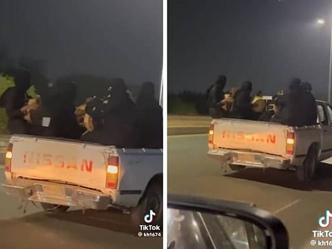 A band of musicians ride on a pickup truck.