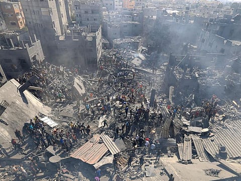 People search for survivors and the bodies of victims through the rubble of buildings destroyed during Israeli bombardment, in Khan Yunis in the southern Gaza Strip on October 26, 2023, amid the ongoing battles between Israel and the Palestinian group Hamas. Thousands of civilians, both Palestinians and Israelis, have died since October 7, 2023, after Palestinian Hamas militants based in the Gaza Strip entered southern Israel in an unprecedented attack triggering a war declared by Israel on Hamas with retaliatory bombings on Gaza. (Photo by Mahmud HAMS / AFP)
