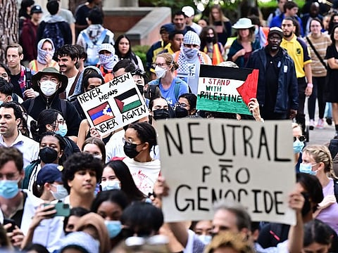 A protester holds a placard showing a Palestinian flag at University of California, Los Angeles