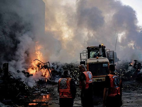 Smoke and fire rise from buildings as rescuers gather amid the destruction in the aftermath of an Israeli strike on Gaza City on October 26, 2023, as battles continue between Israel and the Palestinian Hamas group.
