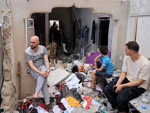 People sit amid the rubble of a building in the aftermath of an Israeli strike on Khan Younis in the southern Gaza Strip on October 29, 2023.