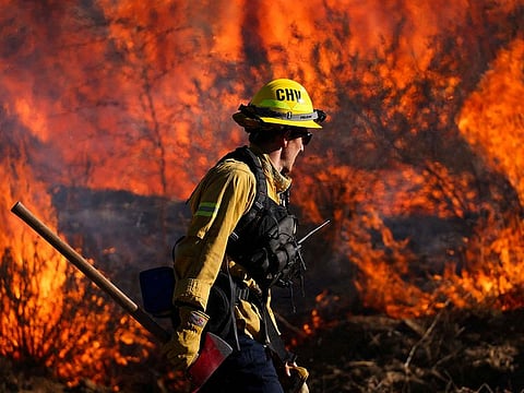 A firefighter works to extinguish the Highland Fire, a wind driven wildfire near Aguanga, California.