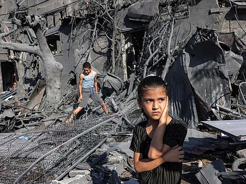 A girl looks on as she stands by the rubble outside a building that was hit by Israeli bombardment in Rafah in the southern Gaza Strip