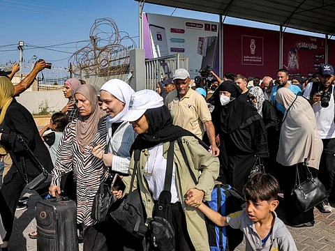 People walk through a gate to enter the Rafah border crossing to Egypt in the southern Gaza Strip on November 1, 2023. Scores of foreign passport holders trapped in Gaza started leaving the war-torn Palestinian territory on November 1.