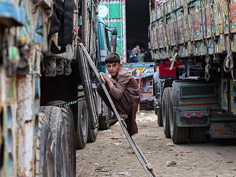 An Afghan refugee boy climbs a truck as he prepares to depart for Afghanistan, at a holding centre in Landi Kotal on November 1, 2023.
