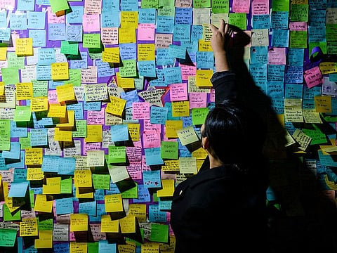 A person attaches a handwritten note next to others left on a board during a vigil in Seoul on October 29, 2023, to mark the first anniversary of the tragic crowd crush that killed 159 people during Halloween celebrations, in Seoul’s popular Itaewon nightlife area a year ago.