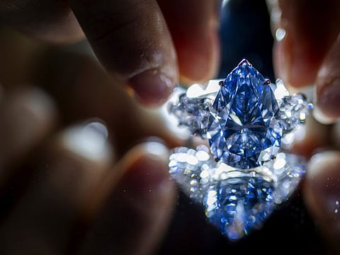 A Christie's employee displays "Bleu Royal," a rare 17.61 carats internally flawless fancy vivid blue pear shaped diamond, during a preview at the Christie's, in Geneva, Switzerland, Thursday, Nov. 2, 2023.