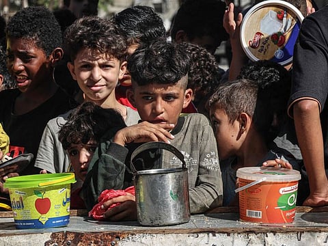 Palestinian children queue up to receive a portion of food at a make-shift charity kitchen in Rafah in the southern Gaza Strip, on November 8, 2023.
