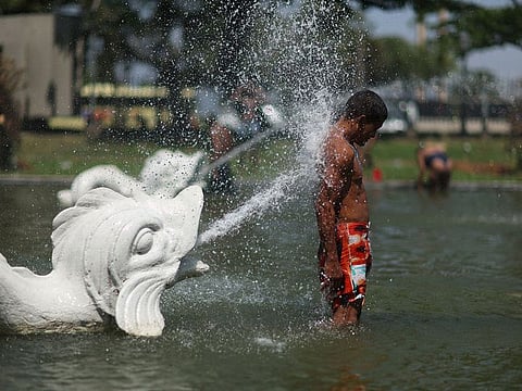 A man cools down in a fountain during a heatwave in Rio de Janeiro, Brazil.